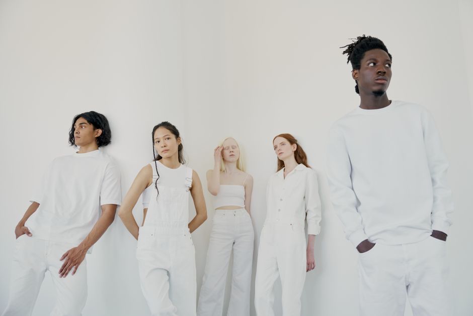 Five diverse individuals posing stylishly in white outfits against a plain background.