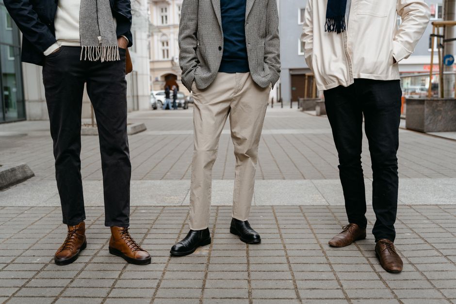 A group of three stylish businessmen standing confidently on an urban street.
