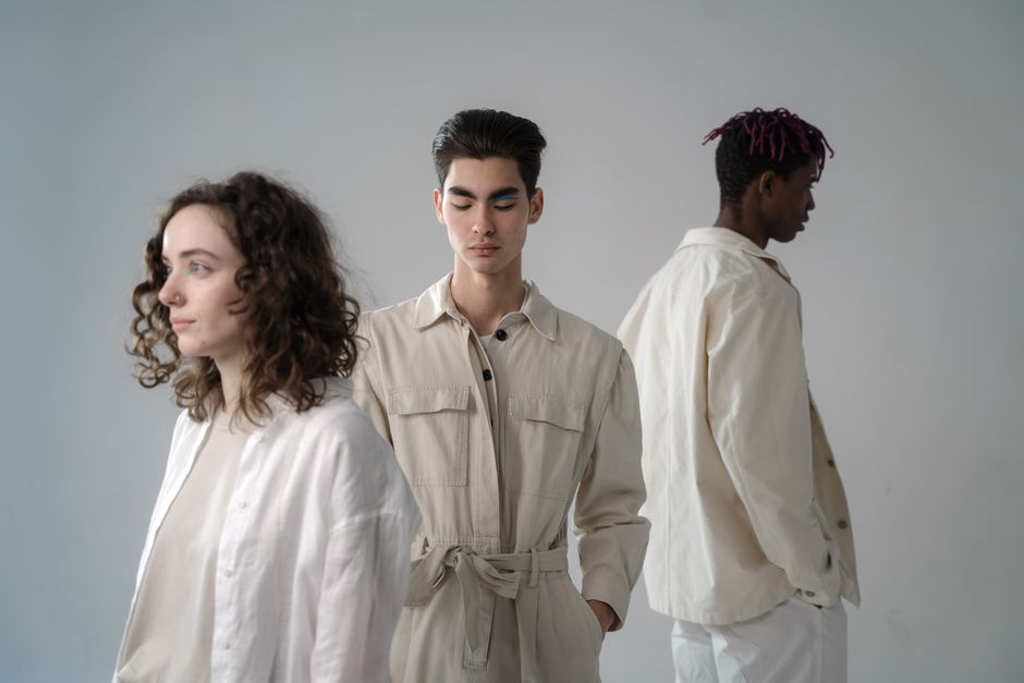 A diverse group of young adults posing in stylish, neutral outfits during a studio photoshoot.