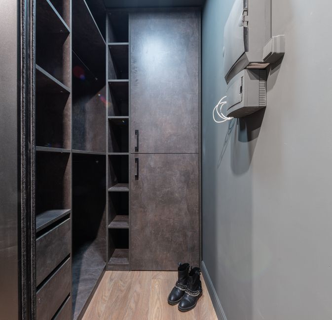 Spacious modern walk-in closet with shelves and leather boots on the floor.