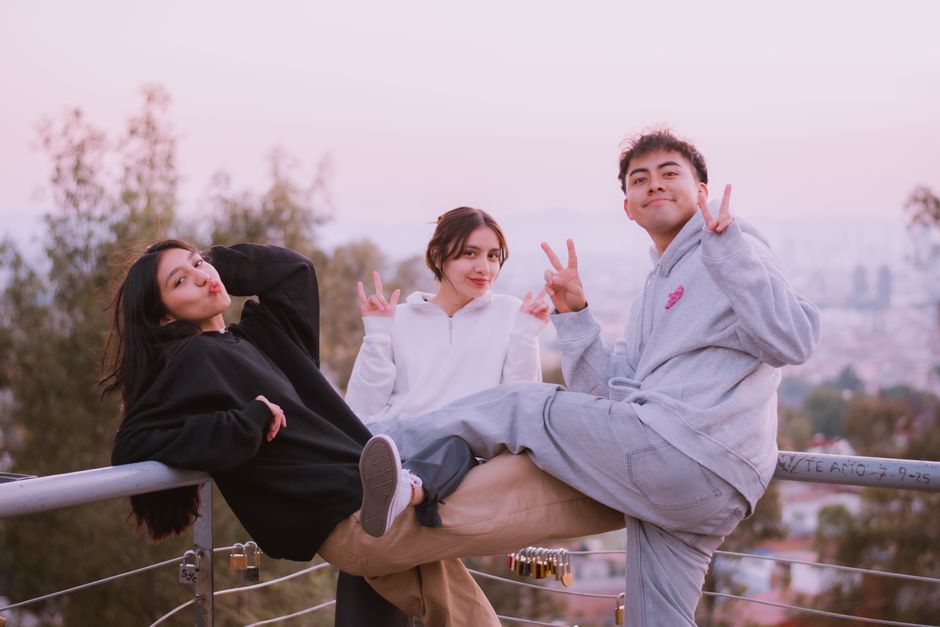 Three friends enjoying a sunset with peace signs in a relaxed outdoor setting.