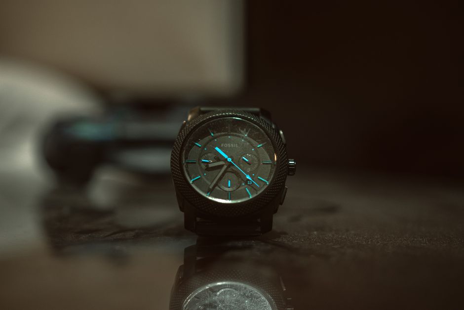 Close-up shot of a Fossil wristwatch with blue accents and industrial design in low lighting.