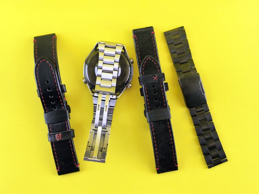 Assorted watch bands including metal and leather on vibrant yellow background.