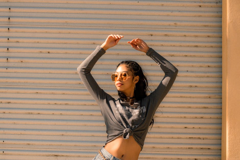 Confident woman in casual fashion posing with sunglasses on a sunny day.