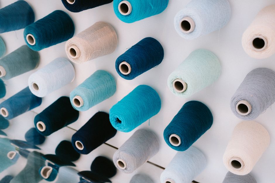 Close-up view of colorful thread spools arranged on a white background, creating an artistic pattern.
