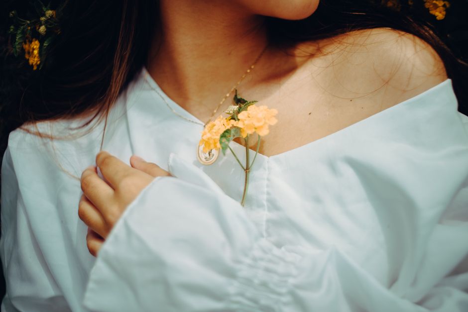 Elegant composition of a delicate flower atop a white blouse, symbolizing simplicity and grace.