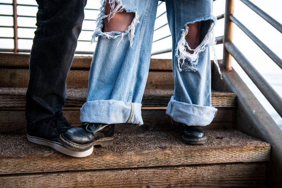 Close-up of stylish legs wearing ripped jeans and boots on outdoor stairs.