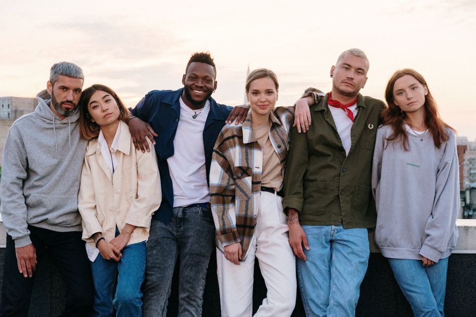 A diverse group of young adults enjoying a casual rooftop gathering at sunset, embracing friendship and unity.