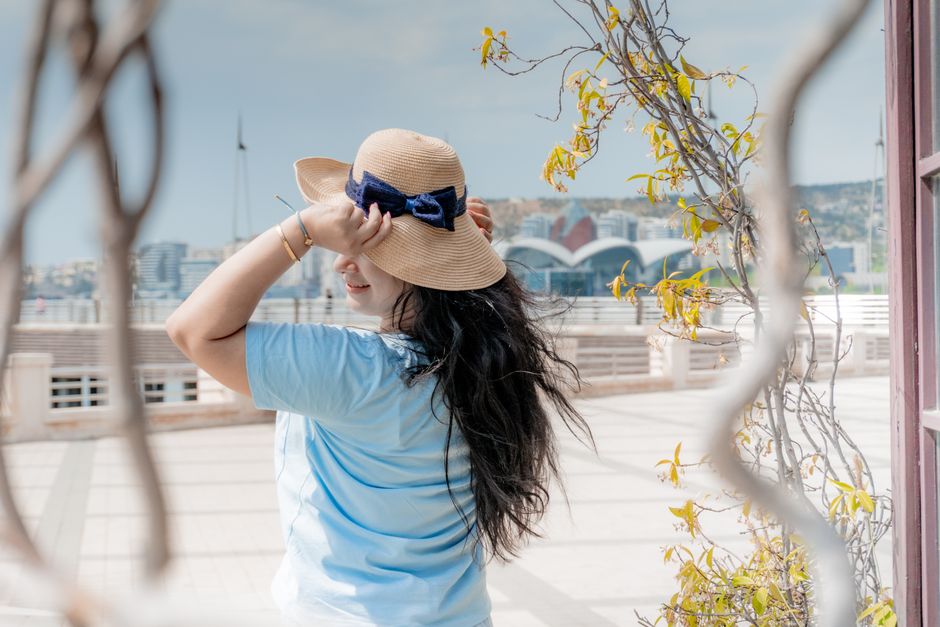 A fashionable woman enjoying a sunny day at the Baku waterfront with city views.