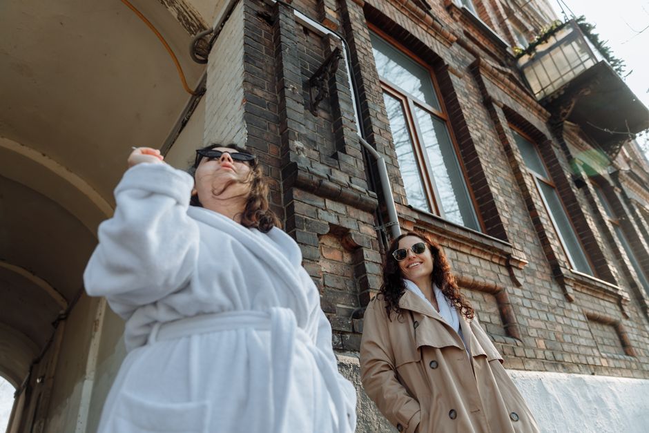 Two women in streetwear with sunglasses enjoying an urban setting.