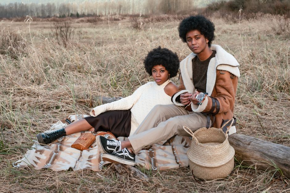 Stylish couple with afro hair enjoying a bohemian picnic outdoors.