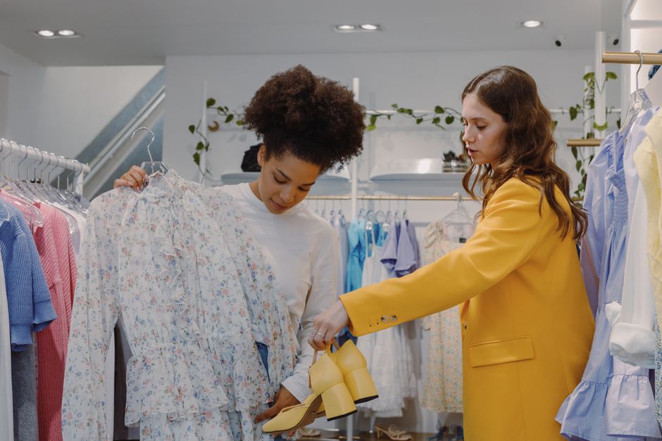 Two women shopping fashionably in a chic boutique with floral and yellow apparel.