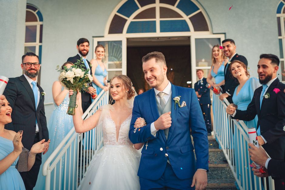 Bride and groom joyously exit wedding ceremony with guests applauding.